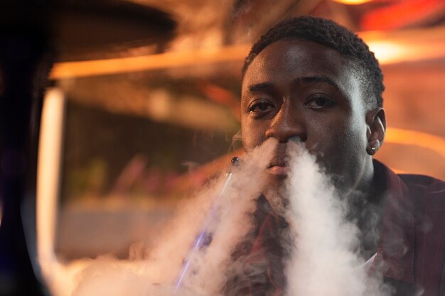 Joven vaping de una pipa de agua en un bar.