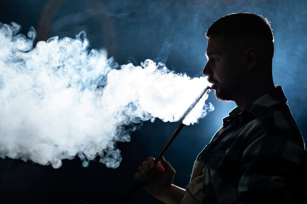 Joven vaping de una pipa de agua en un bar.