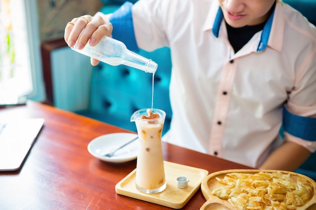 joven vertiendo leche en una jarra de té helado