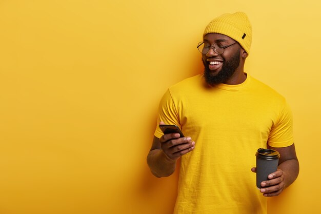 Joven vestido de amarillo con teléfono y taza de café