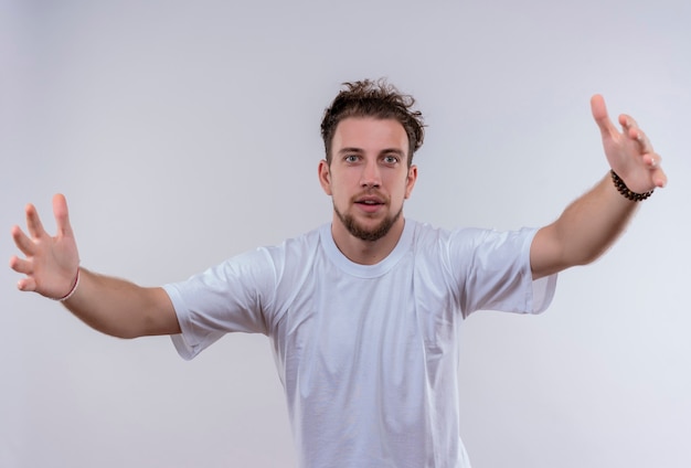 Foto gratuita joven vestido con camiseta blanca que muestra el tamaño en la pared blanca aislada