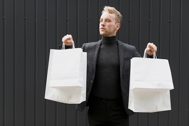 Foto gratuita joven vestido de negro con bolsas de compras