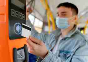 Foto gratuita joven viajando en autobús urbano pagando con tarjeta de autobús