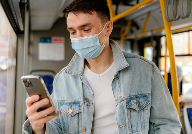 Joven viajando en autobús urbano con smartphone