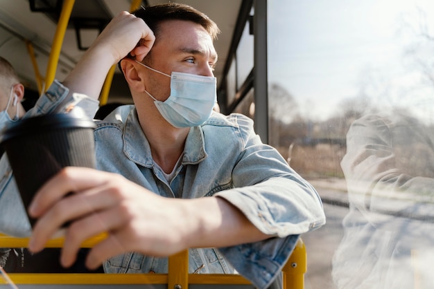 Foto gratuita joven viajando en autobús urbano sosteniendo una taza de café