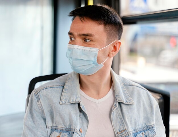 Joven viajando en autobús urbano vistiendo mascarilla quirúrgica