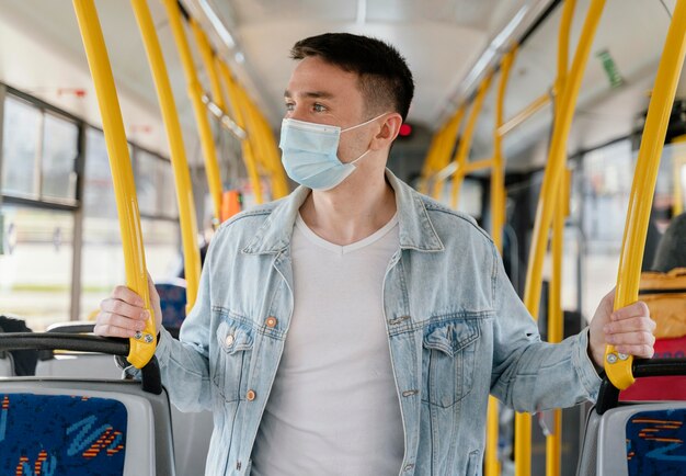 Joven viajando en autobús urbano vistiendo mascarilla quirúrgica