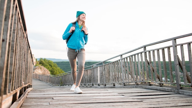 Joven viajero con gorro caminando sobre el puente