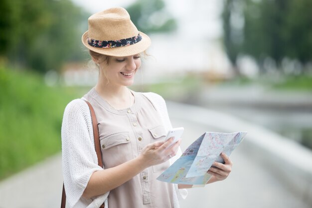 Joven viajero mujer celebración mapa y teléfono durante el viaje al extranjero