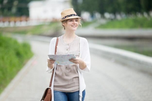 Joven viajero mujer en sombrero de paja caminando con mapa en el viaje