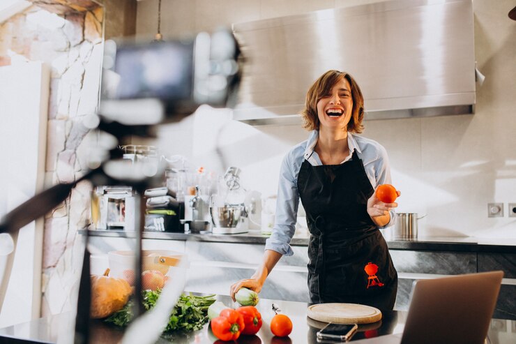 Foto gratuito una joven videoblogger cocinando en la cocina y filmando