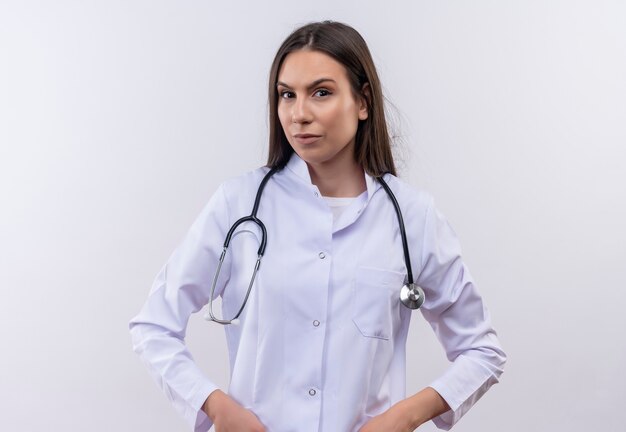 Joven vistiendo bata médica estetoscopio sobre pared blanca aislada