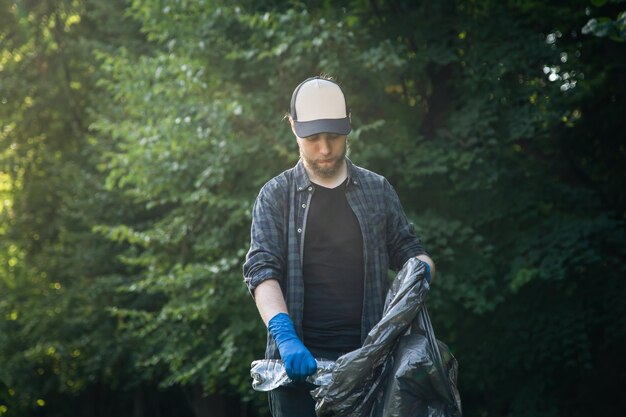 Un joven voluntario limpia botellas en el bosque