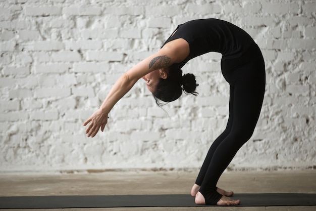 Joven, yogui, atractivo, mujer, Ardha, Chakrasana, posar, loft, backg