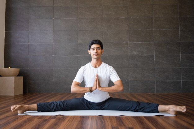 Joven yogui indio haciendo splits en gimnasio