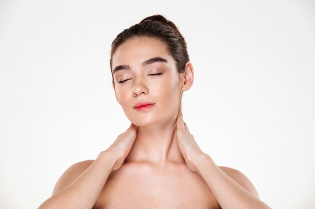 jovencita con cabello en moño y piel limpia descansando en spa haciendo tratamiento de cuidado corporal