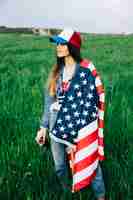 Foto gratuita jovencita en campo con bandera estadounidense