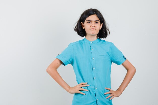 Jovencita cogidos de la mano en la cintura con camisa azul y mirando disgustado