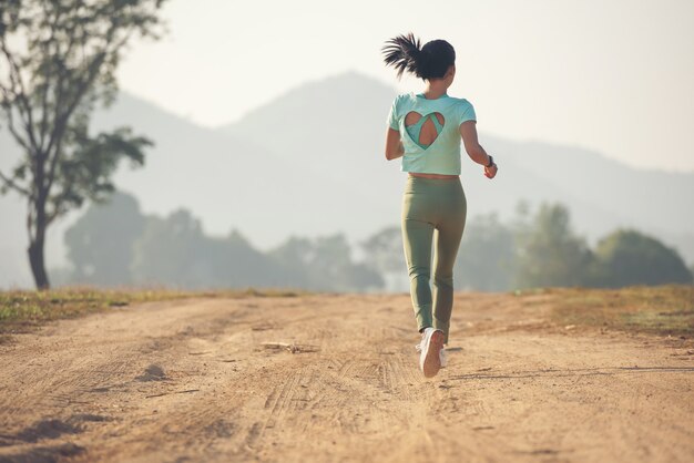 Jovencita disfrutando de un estilo de vida saludable mientras trota por un camino rural, ejercicio y Fitness y entrenamiento al aire libre. Señorita corriendo en un camino rural durante la puesta de sol.