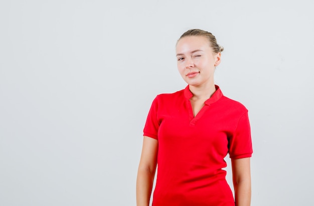 Foto gratuita jovencita guiñando un ojo en camiseta roja y mirando confiado