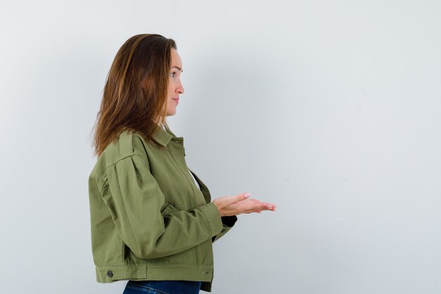 Foto gratuita jovencita haciendo gesto de dar o recibir en chaqueta y lucir linda. .