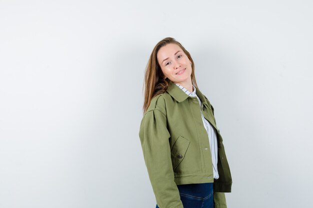 Jovencita mirando a la cámara mientras posa en camisa, chaqueta y parece cautivadora, vista frontal.