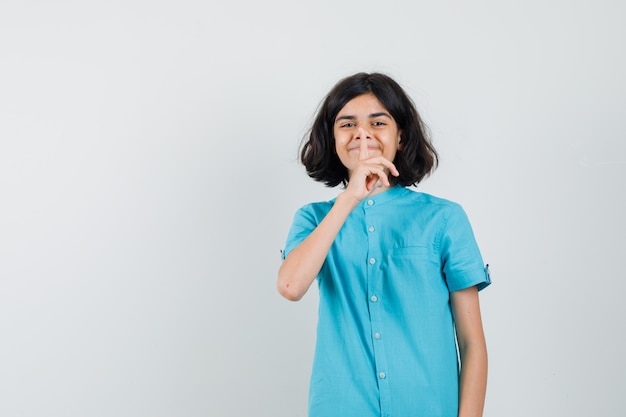 Jovencita mostrando gesto de silencio en camisa azul