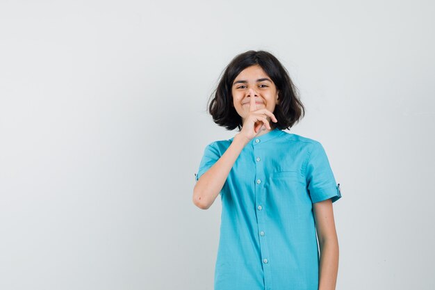 Jovencita mostrando gesto de silencio en camisa azul