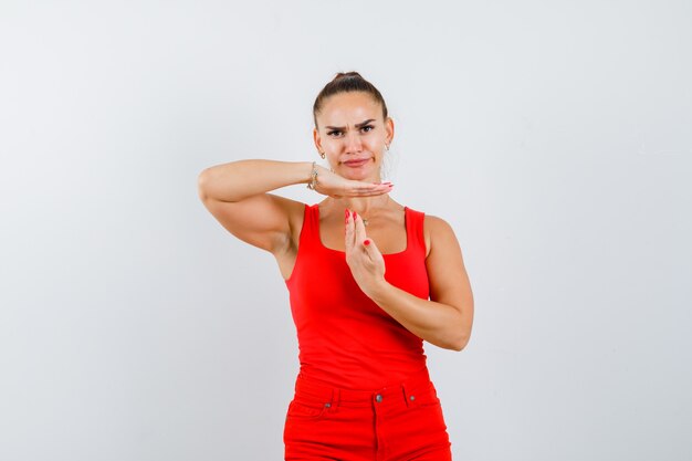 Jovencita mostrando tiempo de espera en camiseta roja, pantalón rojo y luciendo segura de sí misma. vista frontal.