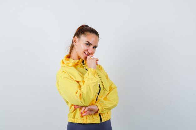 Jovencita posando en chaqueta amarilla y mirando alegre. vista frontal.