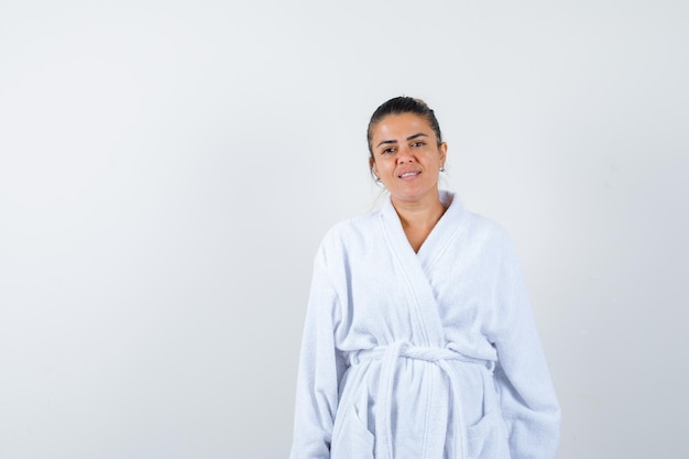 Jovencita posando mientras está de pie en bata de baño y parece confiada