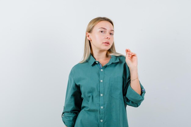 Jovencita posando mientras está de pie en camisa verde y se ve sensible.