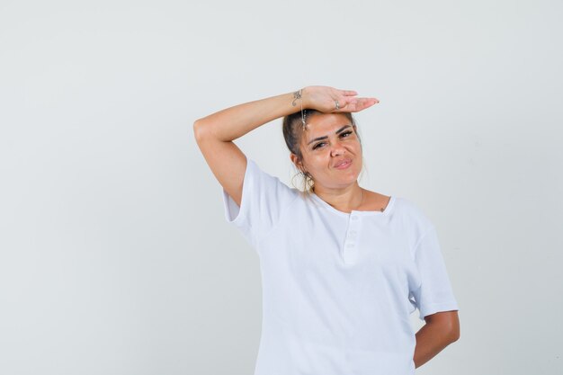 Jovencita posando mientras está de pie en una camiseta y luce seductora