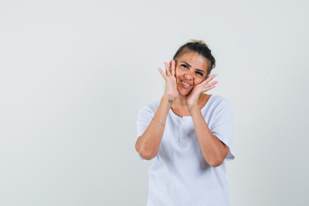 Jovencita posando mientras está de pie en una camiseta y se ve delicada