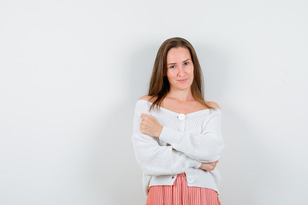 Jovencita posando mientras está de pie en rebeca y falda con aspecto encantador aislado