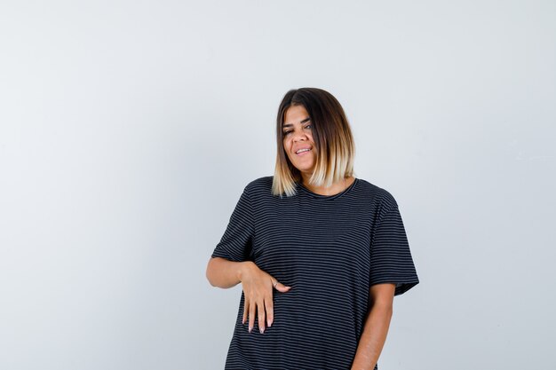 Jovencita posando mientras está de pie en vestido de polo y mirando alegre, vista frontal.