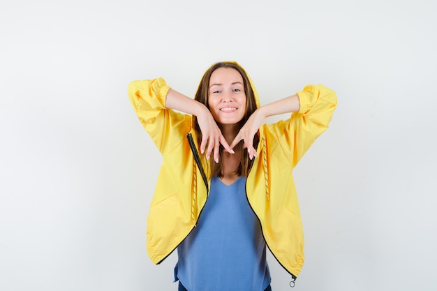 Jovencita posando mientras estira los codos en camiseta, chaqueta y aspecto relajado. vista frontal.