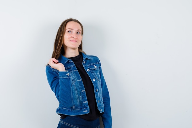 Jovencita posando mientras mira hacia arriba en blusa y parece soñadora. vista frontal.