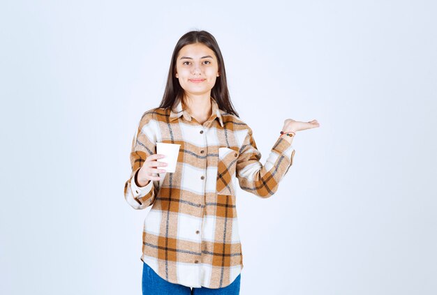 jovencita posando con una taza de té en la pared blanca.