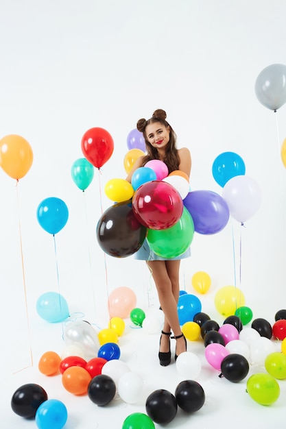 Jovencita en ropa pin-up sosteniendo un montón de globos