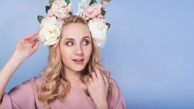 Jovencita rubia emocionada con una hermosa guirnalda de flores