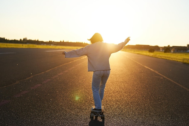 Foto gratuita jovencita se siente feliz en longboard feliz joven patinadora montando su patineta con las manos abiertas