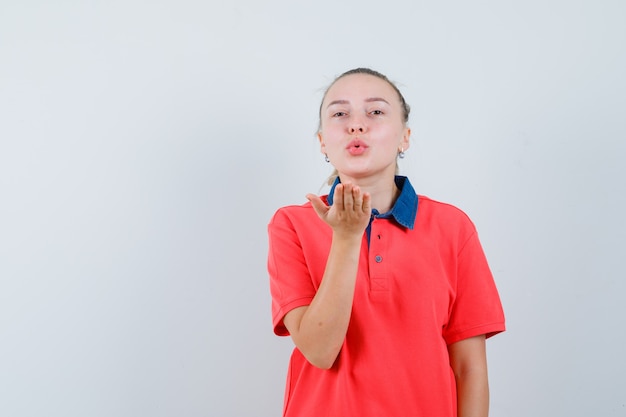 Jovencita soplando aire beso con labios fruncidos en la vista frontal de la camiseta.