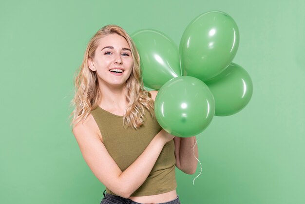 Jovencita sosteniendo globos y mirando al fotógrafo