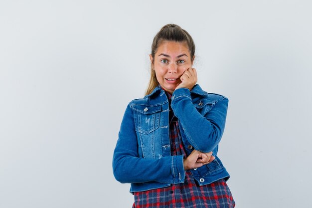 Jovencita sosteniendo la mano en la mejilla en camisa, chaqueta y luciendo linda vista frontal.