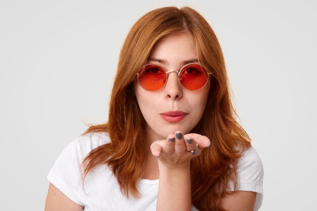 Jovencita te lanza un beso de aire, usa elegantes gafas de sol