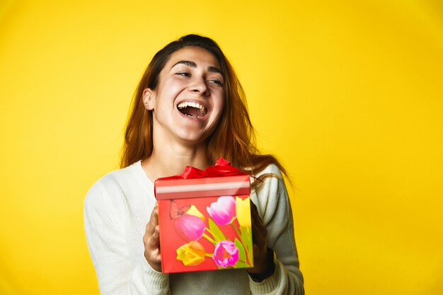 Jovencita tiene un regalo y tiene una mirada muy feliz de pie