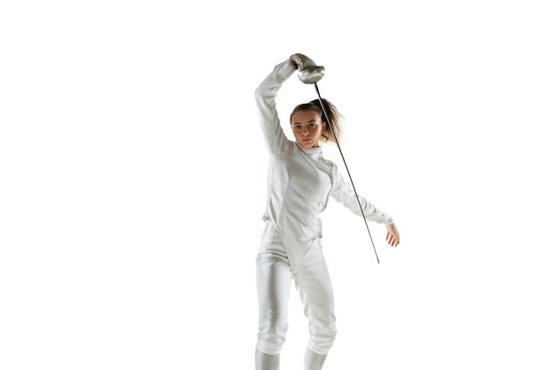 Jovencita en traje de esgrima con espada en mano aislado en la pared blanca