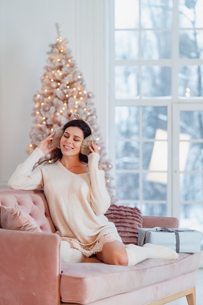 Jovencita vestida de blanco en el sofá en Navidad