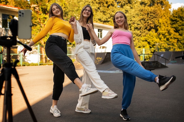 Foto gratuita jóvenes adolescentes grabando carretes de sí mismas al aire libre para las redes sociales